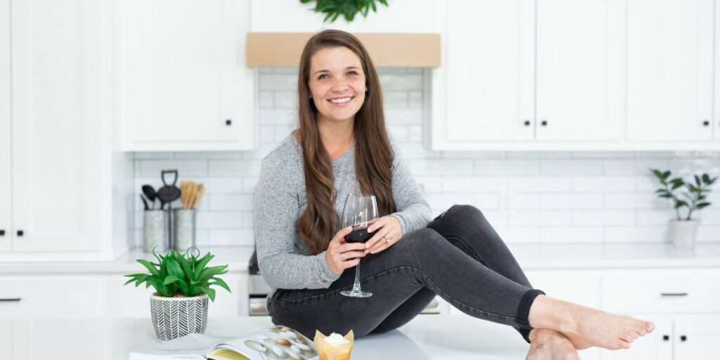 madison sitting on a counter holding a wine glass