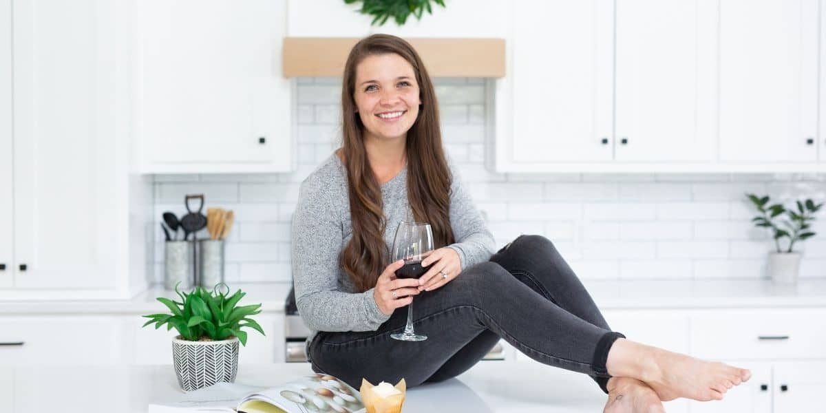 madison sitting on a counter holding a wine glass