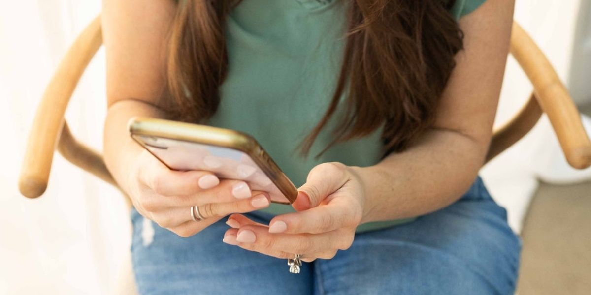 woman in green blouse holding a cell phone.